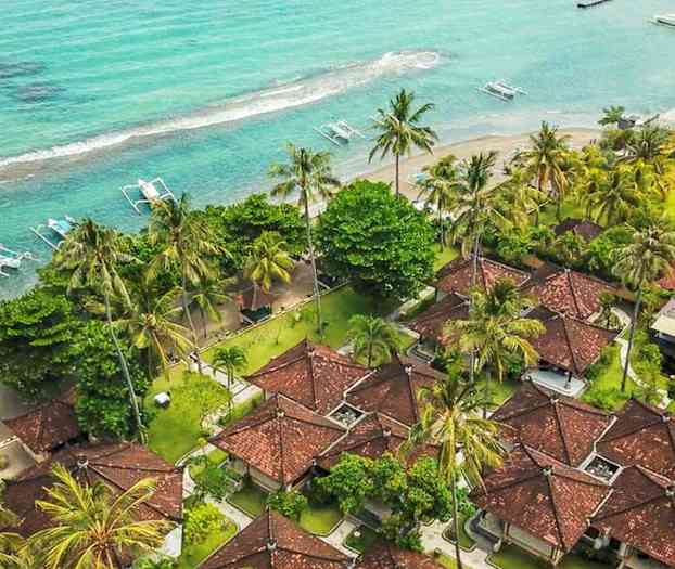 Luftfoto av en strandort med röda hustak, omgiven av palmer och nära ett turkost hav. (AI-genererad text)