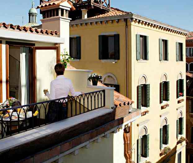 Person på balkong med utsikt över byggnader. (AI-genererad text)