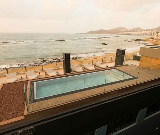 Rooftoppool med solstolar och utsikt över havet och stranden. (AI-genererad text)