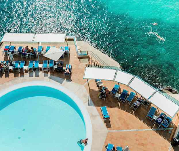 Solstolar och en pool vid havet sett från ovan. (AI-genererad text)