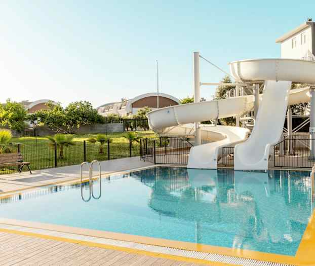 En pool med två vita vattenrutschbanor. (AI-genererad text)