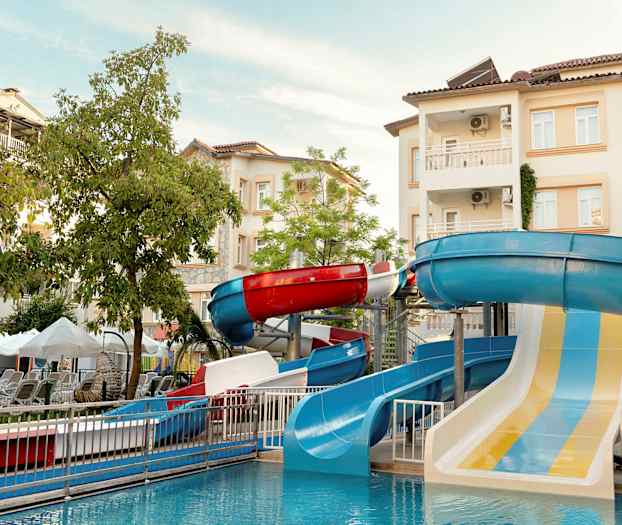 Bild av en vattenpark med vattenrutschbanor och byggnader i bakgrunden. (AI-genererad text)