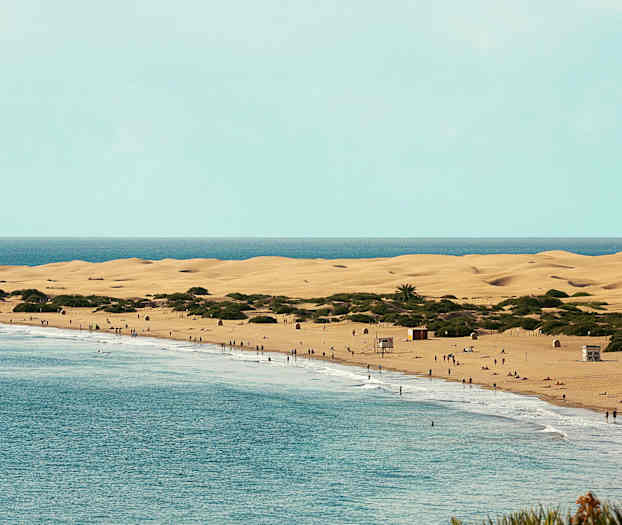 En strand med sanddyner och människor vid vattnet. (AI-genererad text)