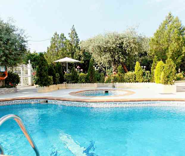 En utomhuspool omgiven av grönska och träd. (AI-genererad text)