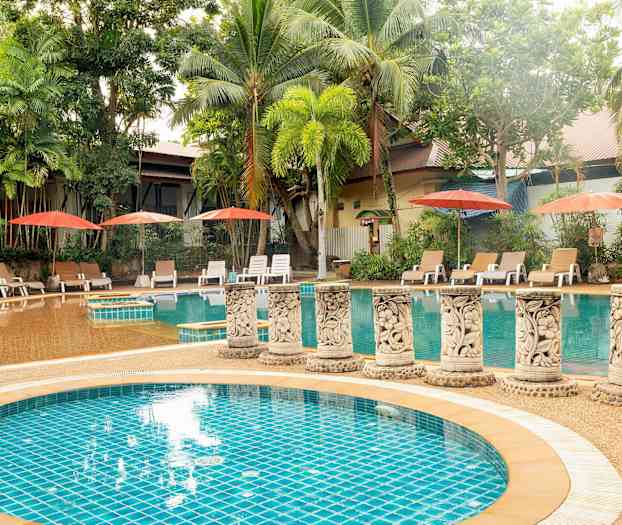 En utomhuspool omgiven av palmer och solstolar med parasoller. (AI-genererad text)