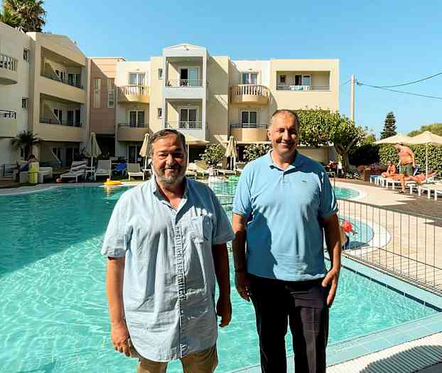 Personer står vid poolen framför ett hotell. (AI-genererad text)