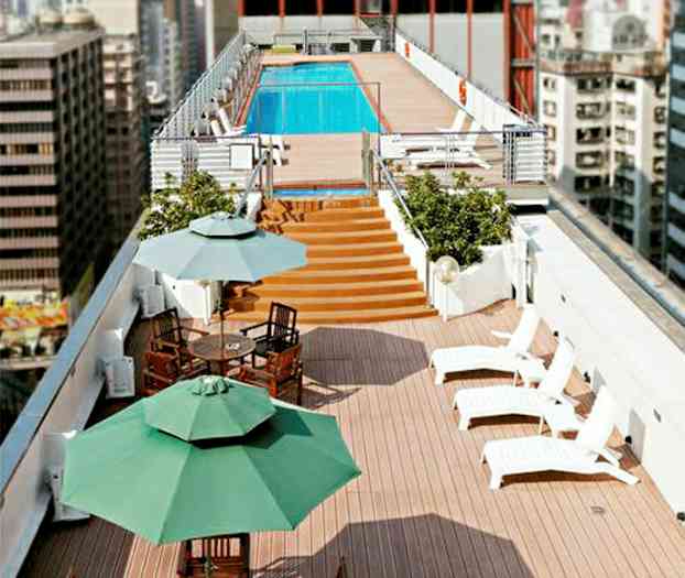 En takterrass med solstolar, matbord och parasoller samt en pool i bakgrunden. (AI-genererad text)