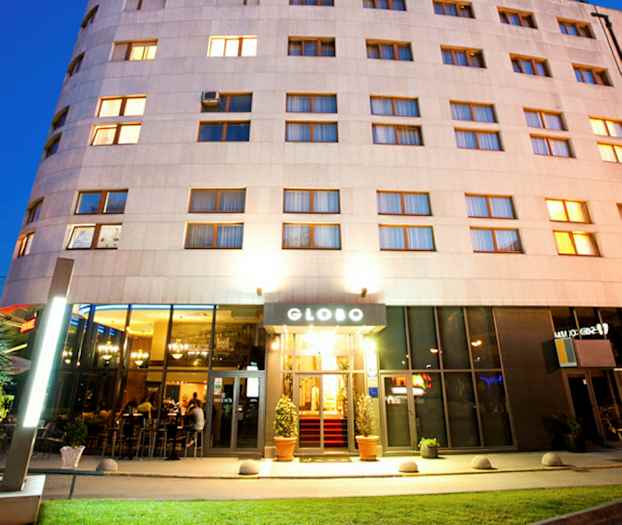 Ett hotell med upplyst fasad och entré, fotograferat i skymningen. (AI-genererad text)