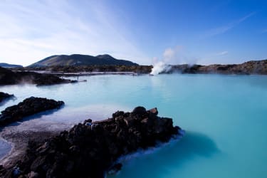 En ångande turkosblå lagun bland vulkaniska klippor på Island.