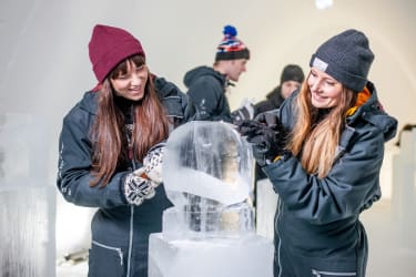Två personer gör en isskulptur på Icehotel - en av Vings konferensaktiviteter på hotellet
