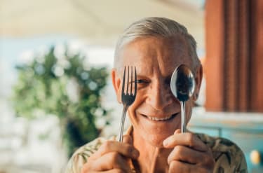 En man håller upp en gaffel och en sked framför ansiktet.