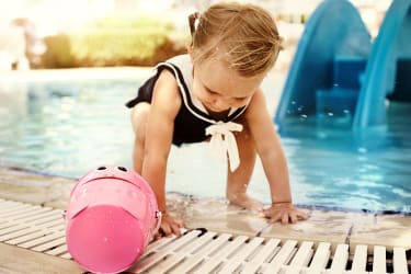 Flicka leker med en hink vid poolkanten