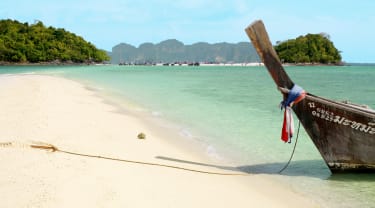 Strand, hav och en båt i Thailand