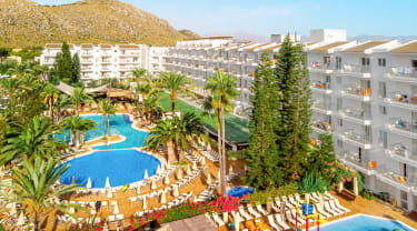 Översiktsbild på VIVA Sunrise, Mallorca. Poolområde och restaurang omgivet av palmer och hotellbyggnader.