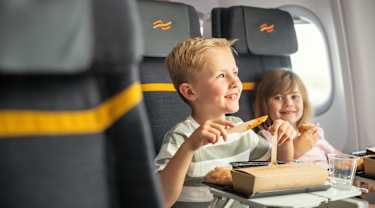 Två barn äter ombord på ett flygplan