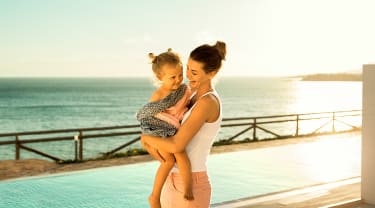 mamma och dotter kramas framför en pool