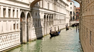 En kanal mellan byggnaderna i Venedig, där två gondoler färdas.