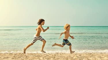 Två killar springer på stranden