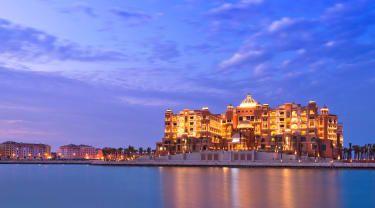 Hotellet Marsa Malaz Kempinski i Doha ligger precis vid vattnet och är upplyst i skymningen.