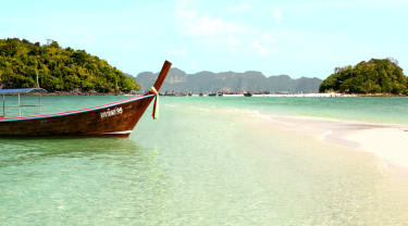 Longtailbåt vid en strand i Thailand