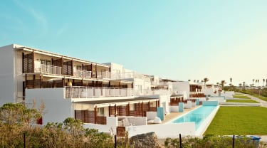 Översiktsbild från Sunwing Kallithea Beach, Rhodos. Låga hotellbyggnader med balkong och swimout-rum i bottenplan.