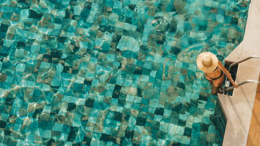 En kvinna iförd solhatt är på väg ner i en pool