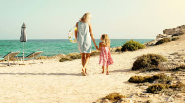 Mor och dotter går på stranden