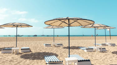 Solstolar på stranden under parasollar