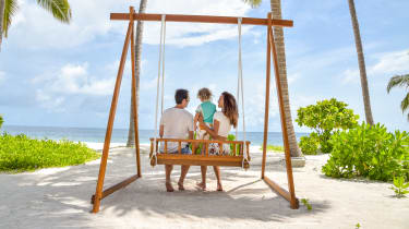 Familj sitter i en gunga på strand