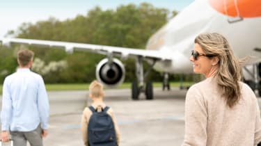 Två vuxna och ett barn på väg mot ett flygplan
