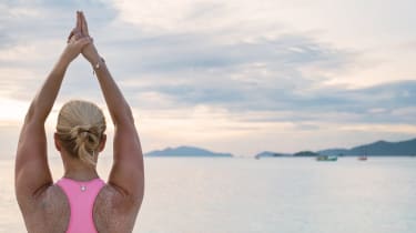kvinna gör yoga ute på en brygga