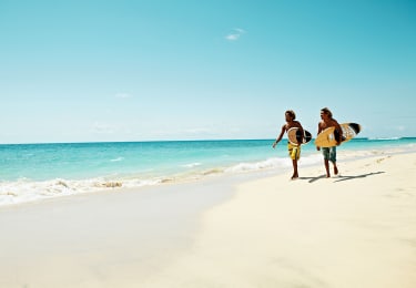Två personer går på en solig strand på Kap Verde