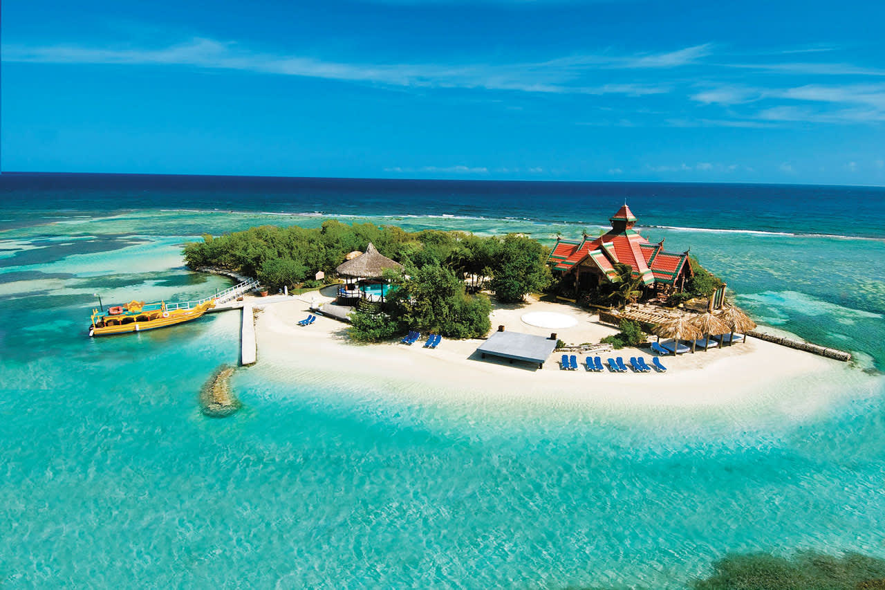Hotellets ö med sandstrand, pool, solstolar och restaurang.