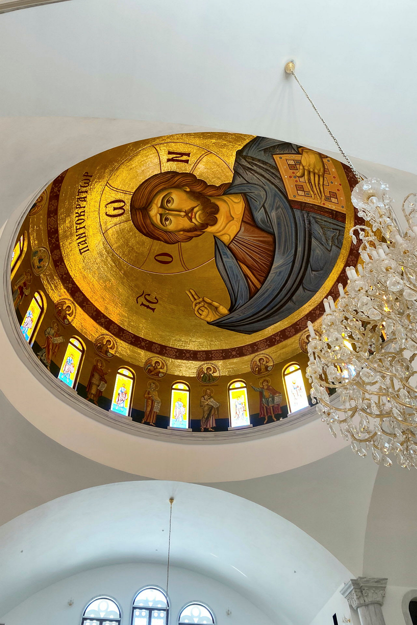 Interiör av en kyrka med ett dekorerat tak i gyllene mosaik och en ljuskrona. (AI-genererad text)