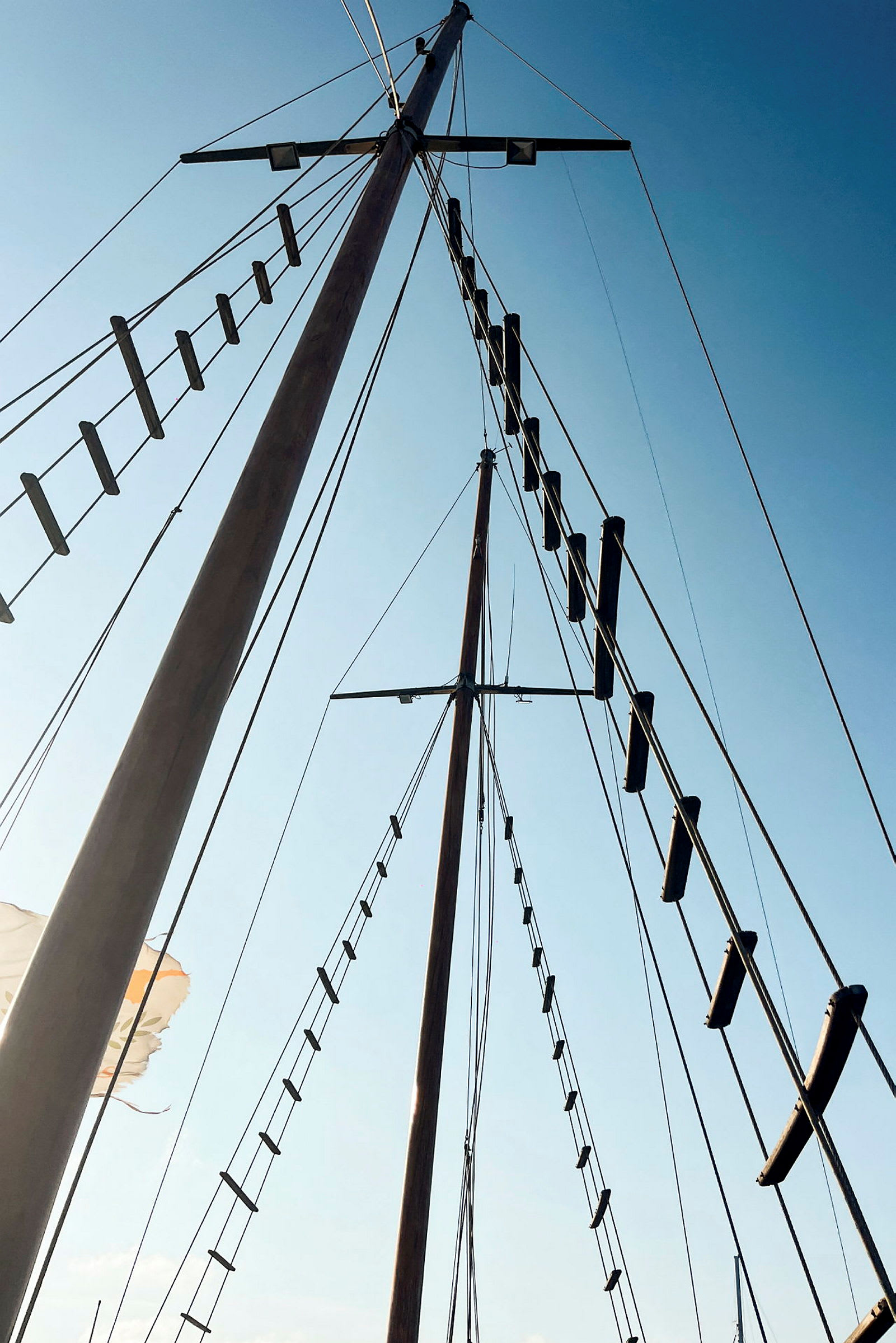 Bilden visar segelfartygets master och rigg mot en blå himmel. (AI-genererad text)