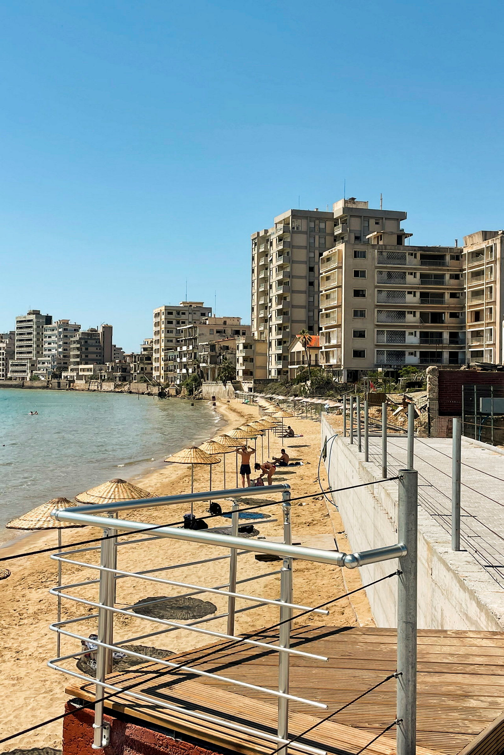 Strand med parasoller och byggnader i bakgrunden. (AI-genererad text)