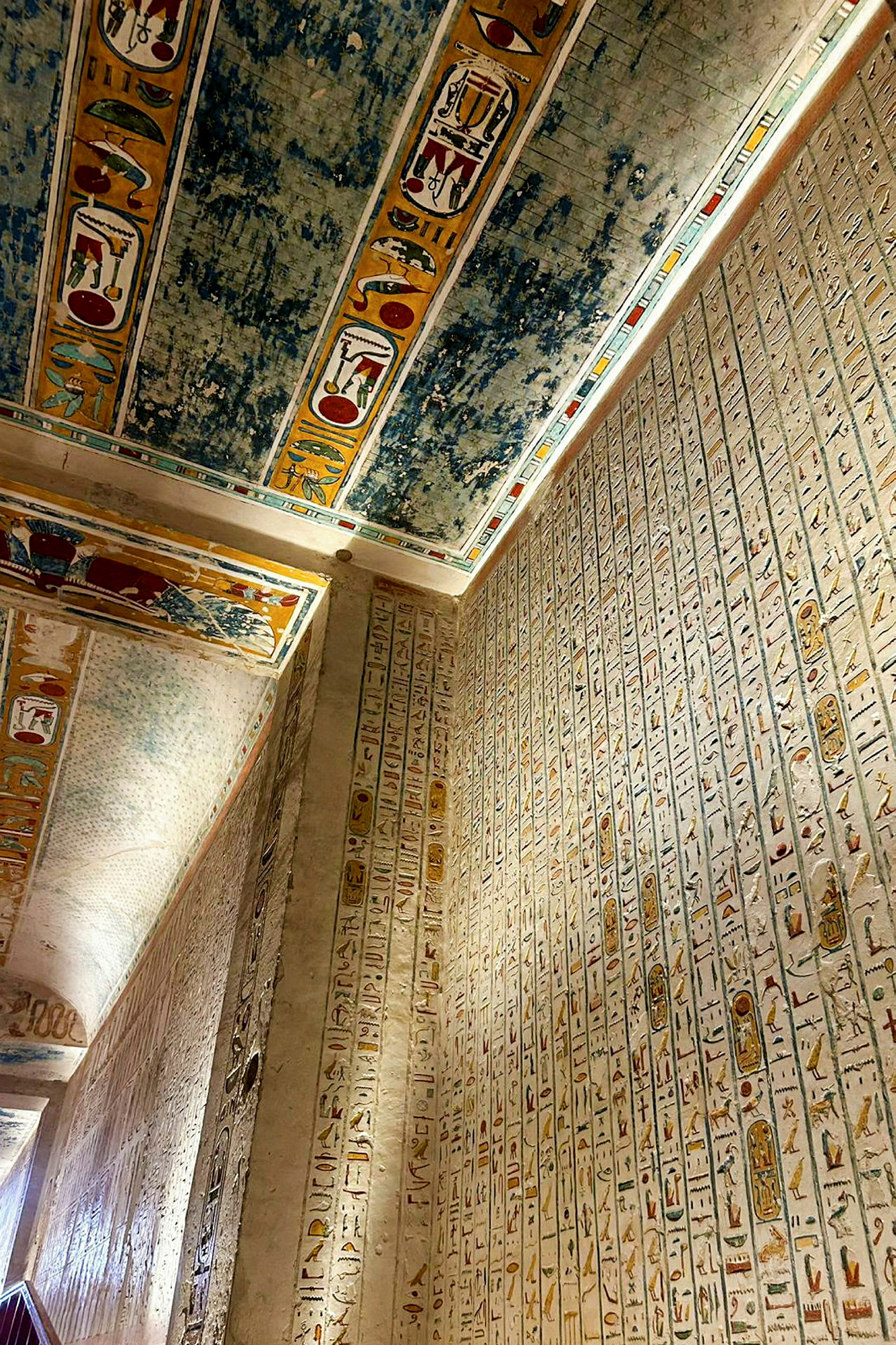 En vägg täckt med hieroglyfer och ett tak med färgglada dekorationer i en gammal egyptisk struktur. (AI-genererad text)