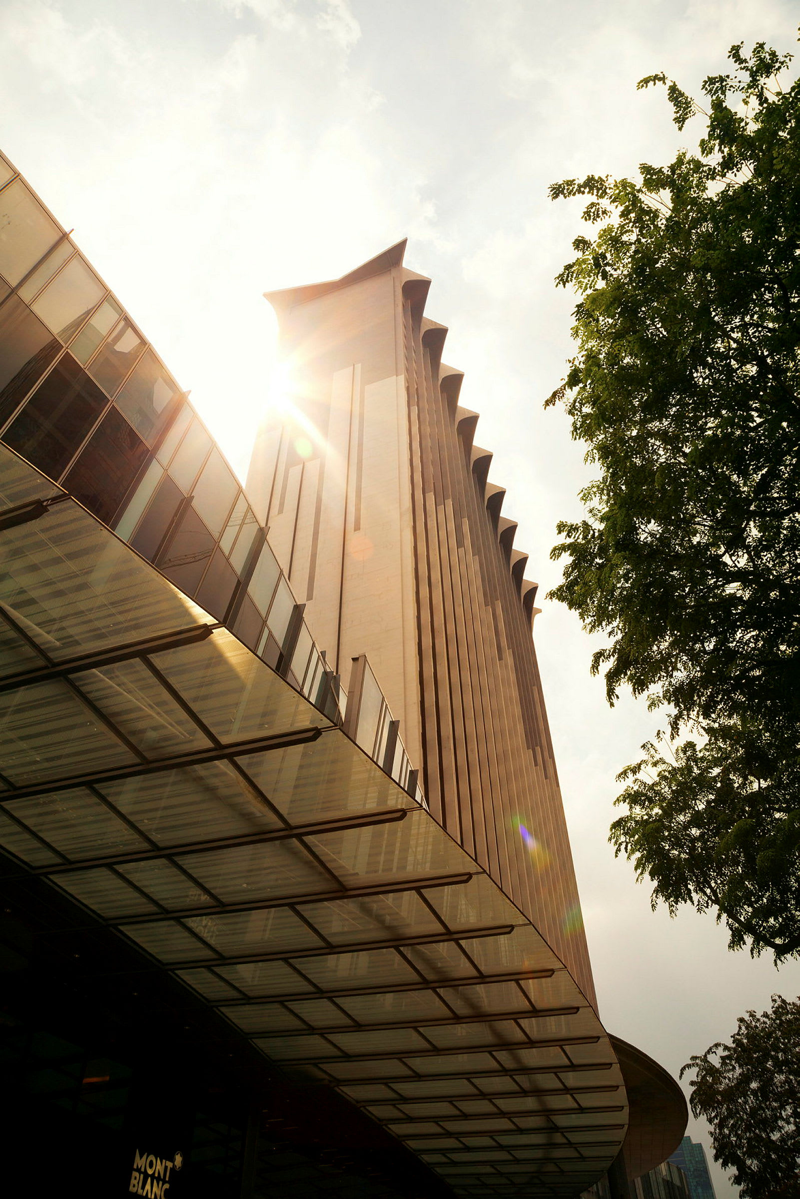 Ett höghus med en modern arkitektonisk stil sett från marknivå under en klar himmel. (AI-genererad text)