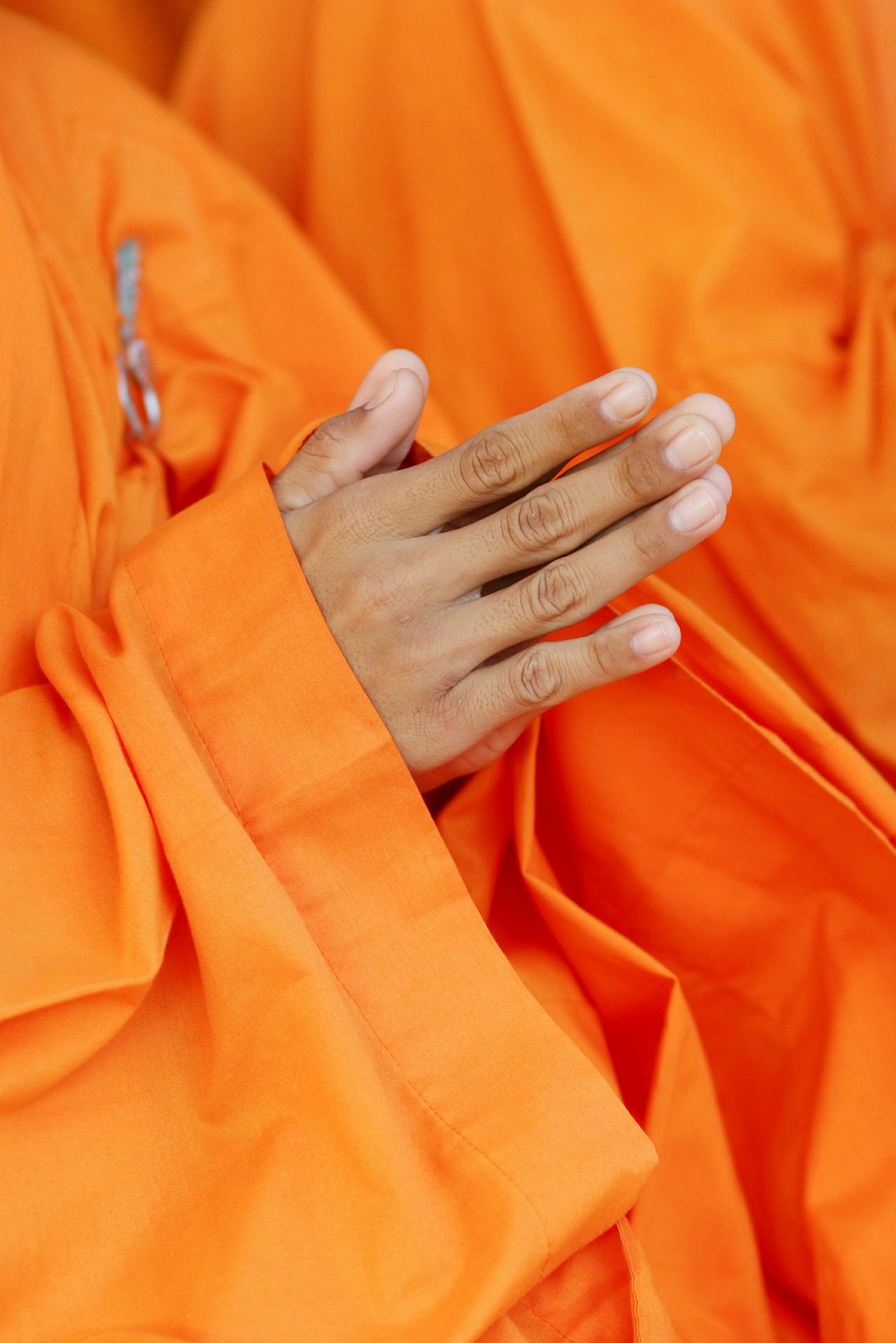 En hand klädd i orange tyg i en böneposition. (AI-genererad text)