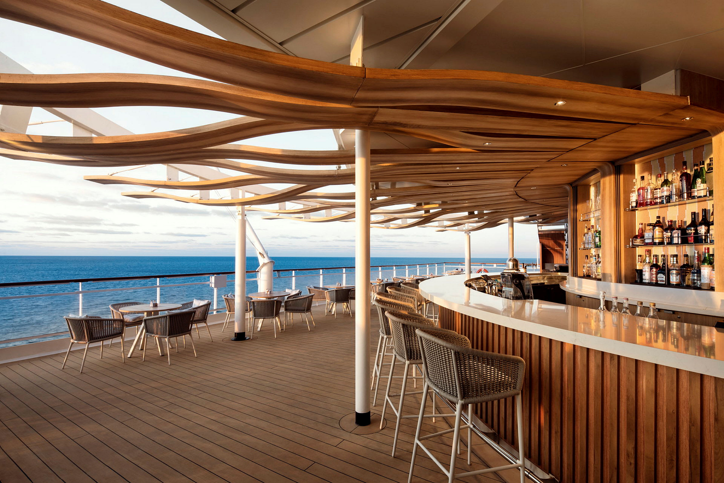 Utomhusbar med stolar och bord på en terrass vid havet. (AI-genererad text)