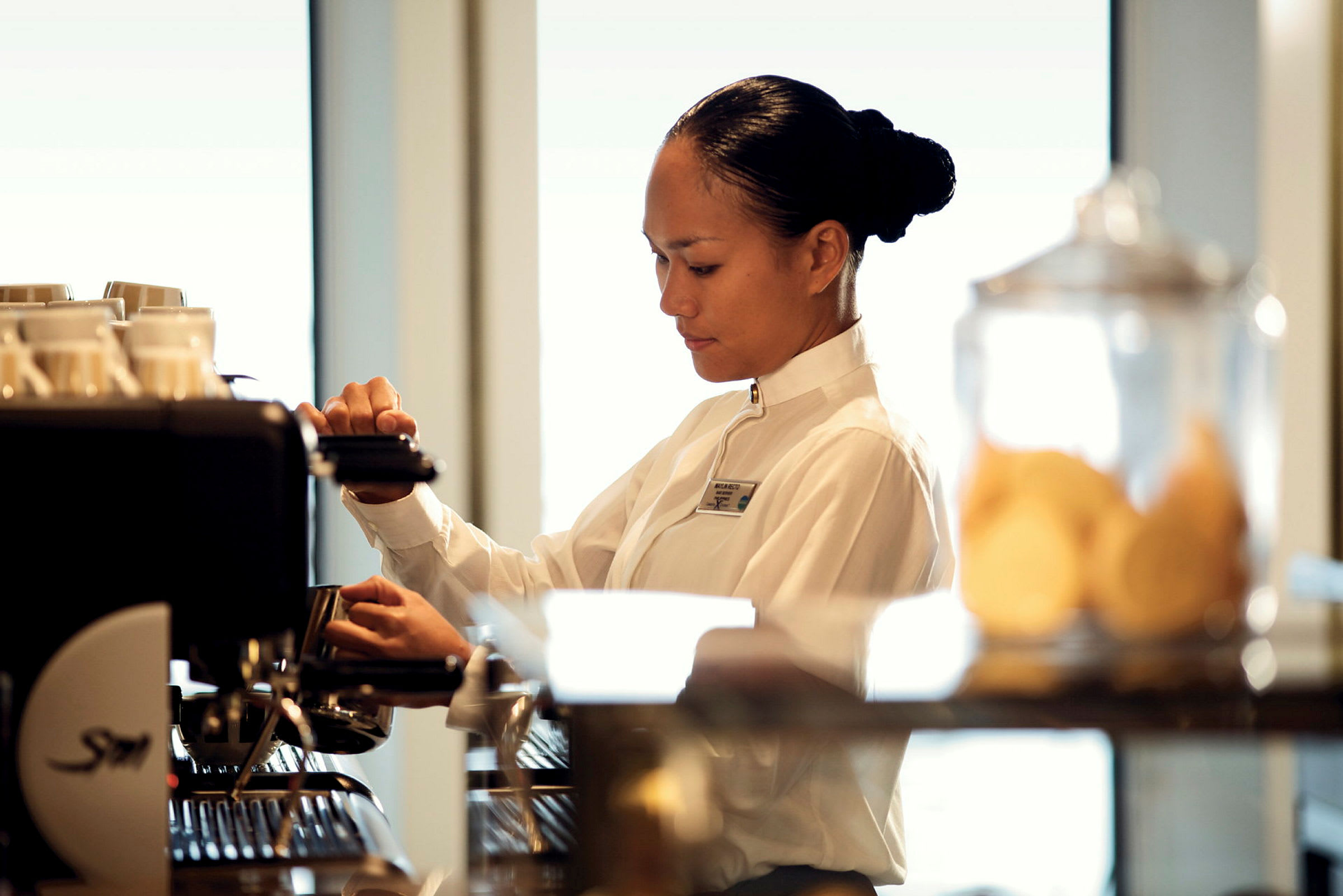 En person i uniform står vid en kaffemaskin och förbereder dryck. (AI-genererad text)