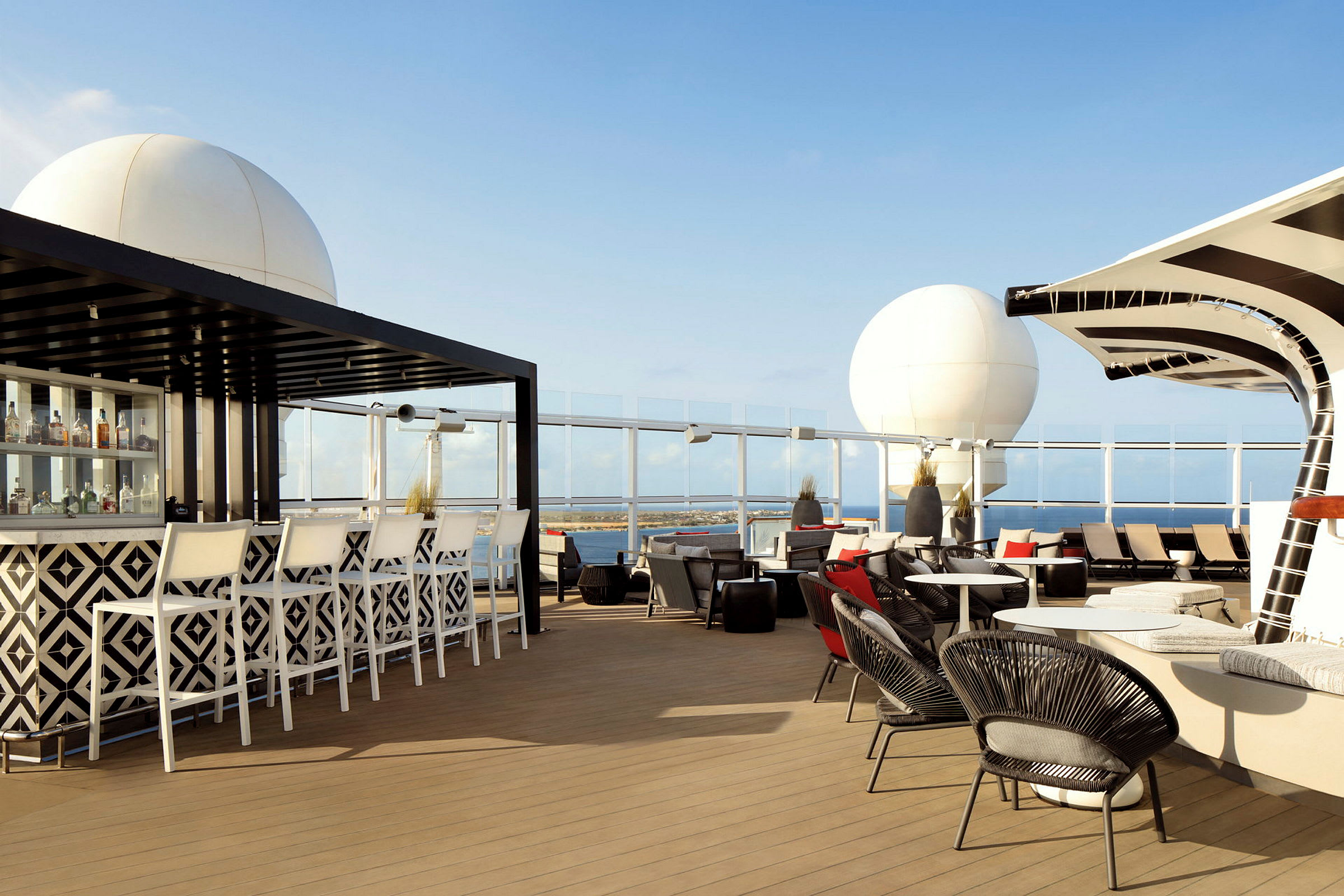 Utomhusområde med bar, sittplatser och solstolar under en klarblå himmel. (AI-genererad text)
