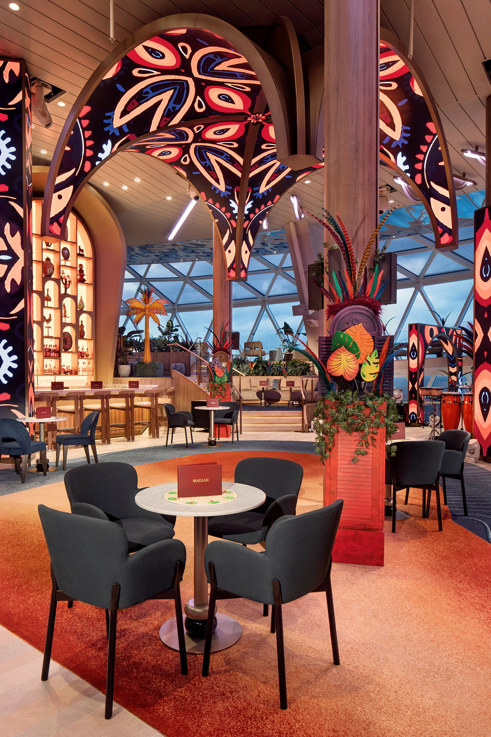 En inredning av en färgglad och modern restaurang med sittplatser, dekorativa växtarrangemang och uppseendeväckande takdetaljer. (AI-genererad text)