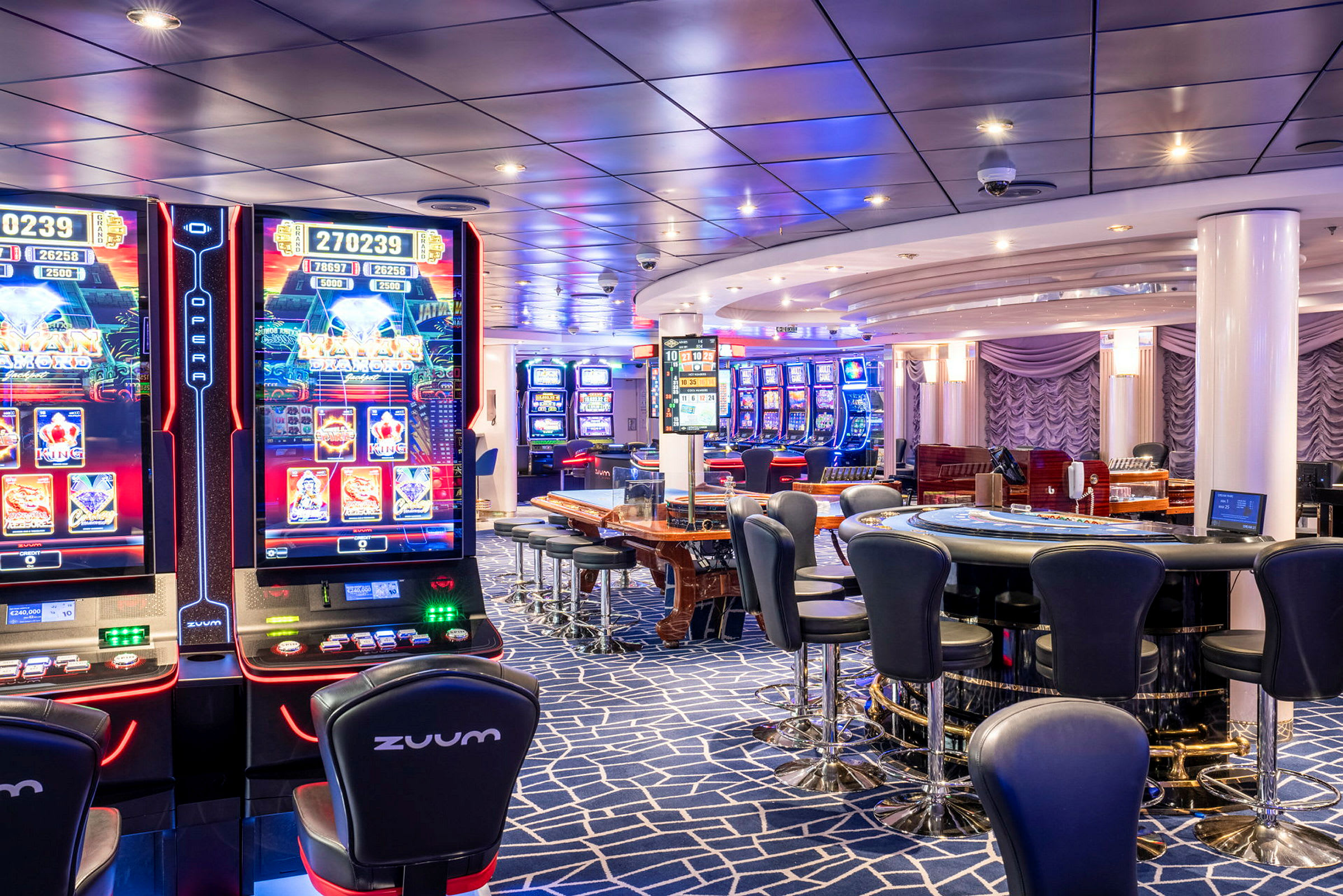 En interiör av ett casino med spelautomater, bord för kortspel och sittplatser. (AI-genererad text)