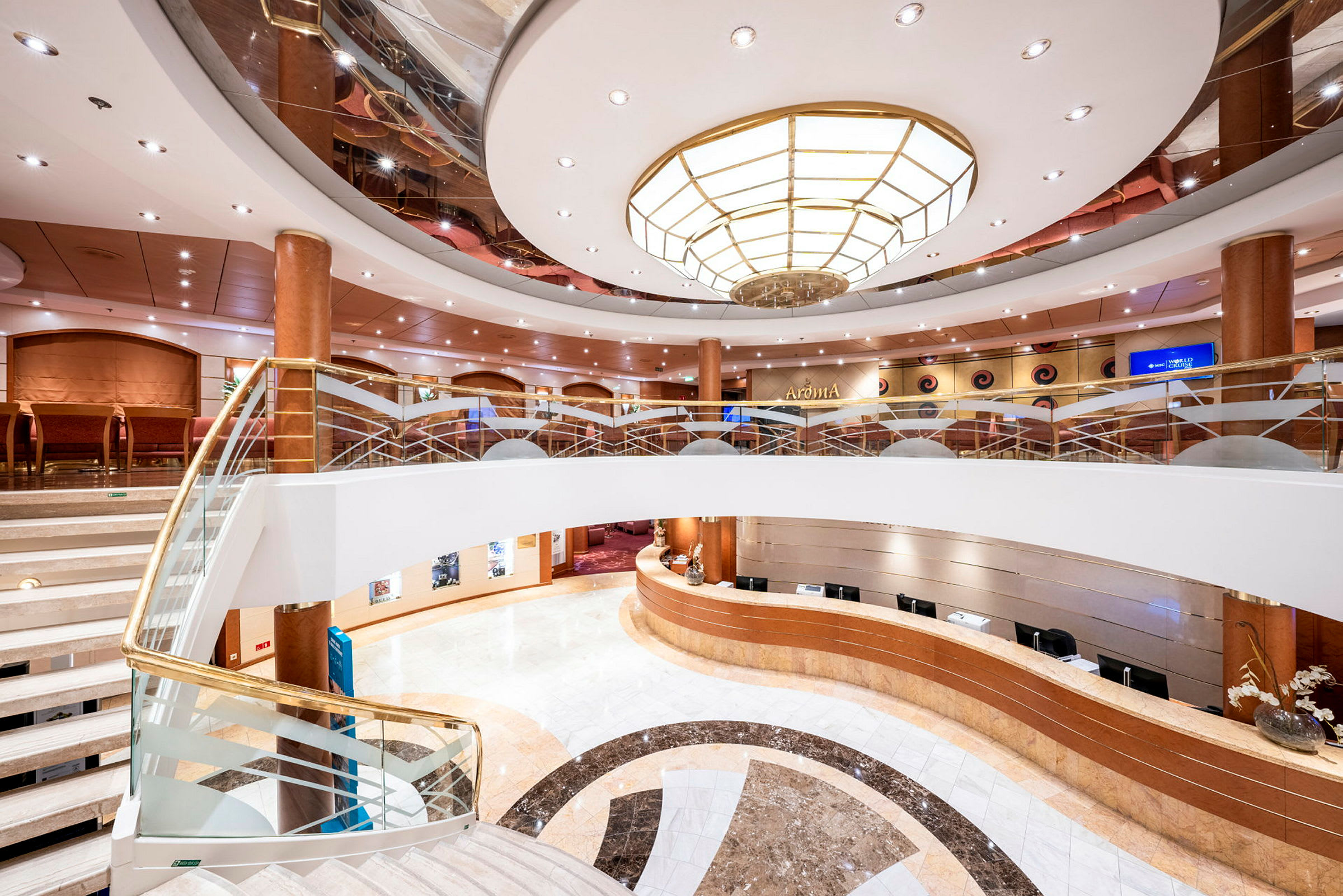 Interiör av en elegant lobby med receptionsdisk, trappa och modern taklampa. (AI-genererad text)