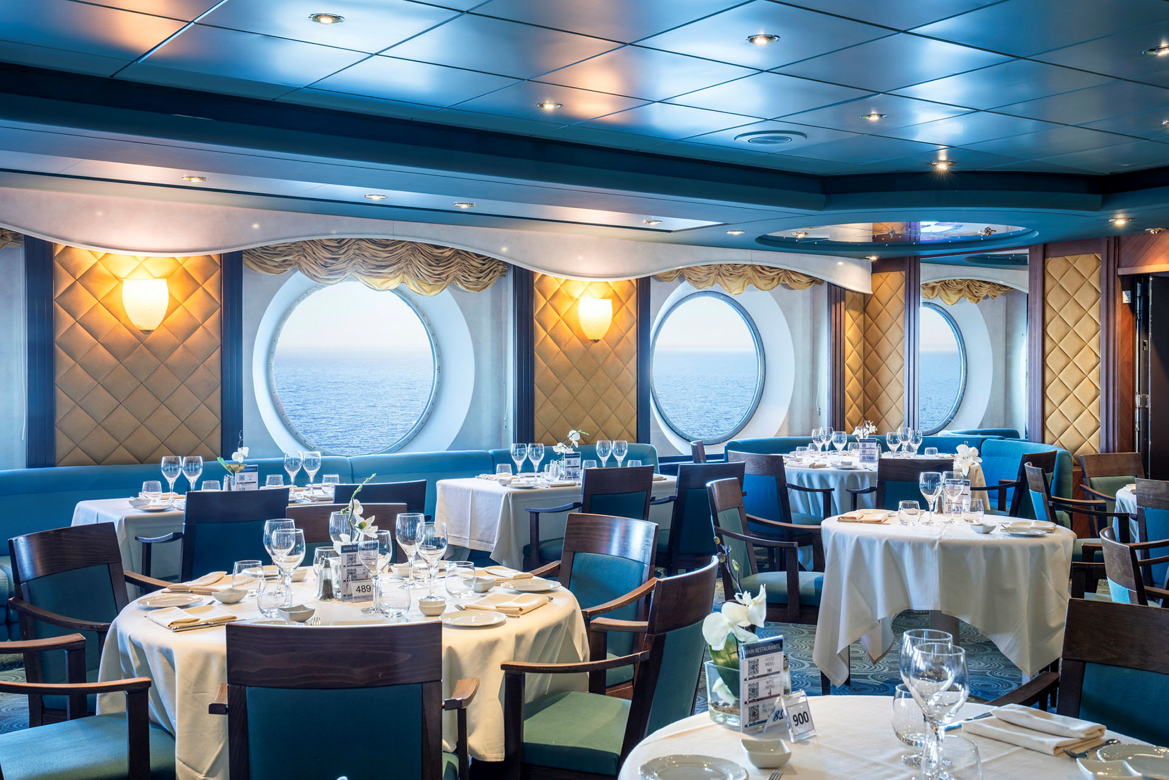 Restaurang med dukade bord, stora fönster med havsutsikt. (AI-genererad text)