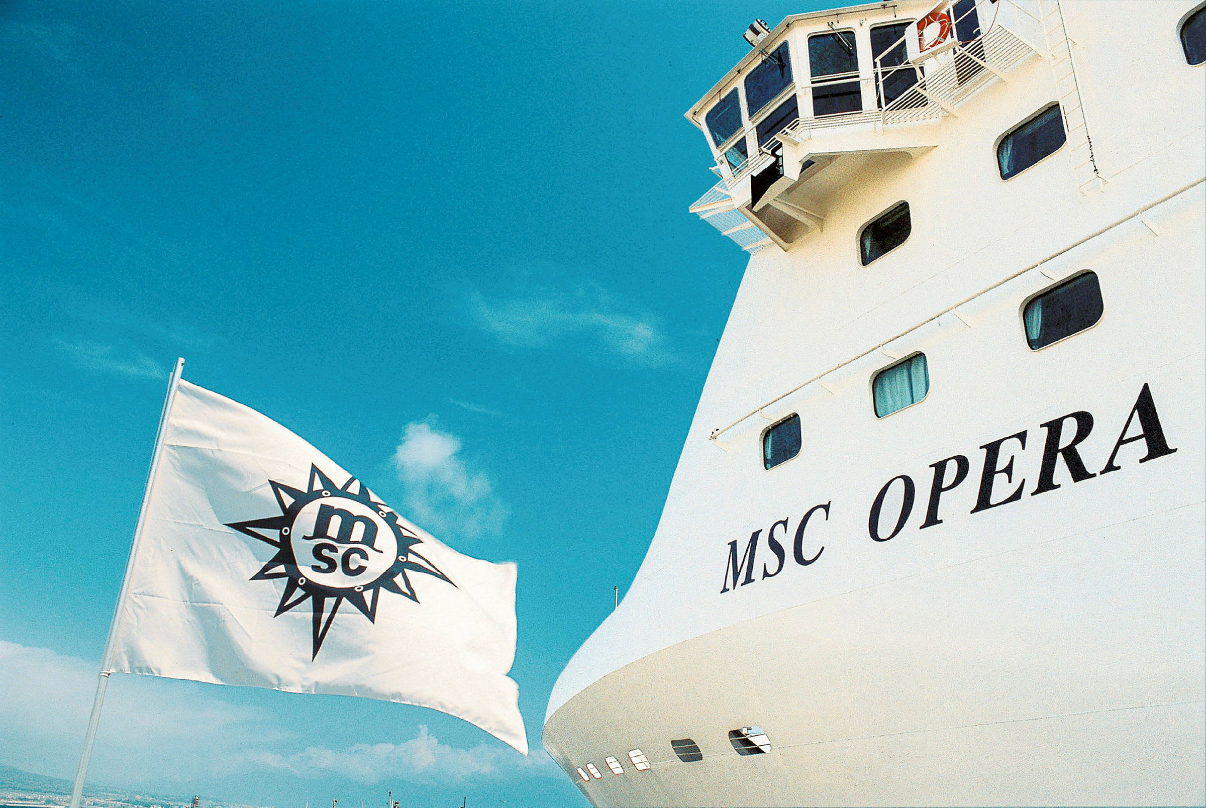 Bild av fartyget MSC Opera med dess namn tydligt visat samt ett vitt flagg med MSC-logotypen hissat. (AI-genererad text)