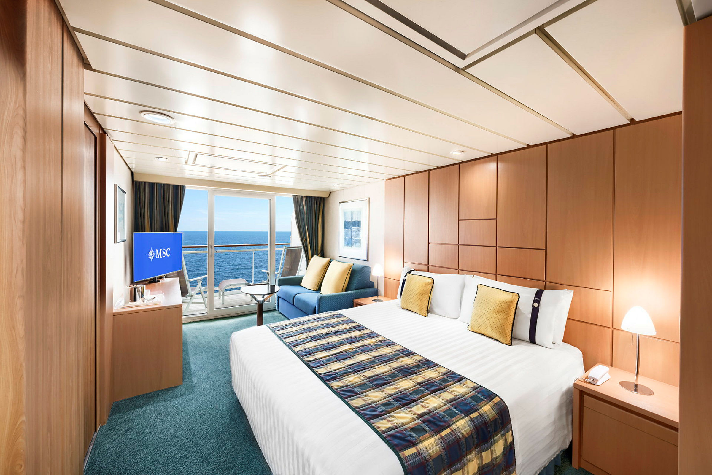Bild av ett rymligt och elegant inrett hotellrum med stor säng, sittgrupp och utsikt över havet genom glasdörrar. (AI-genererad text)
