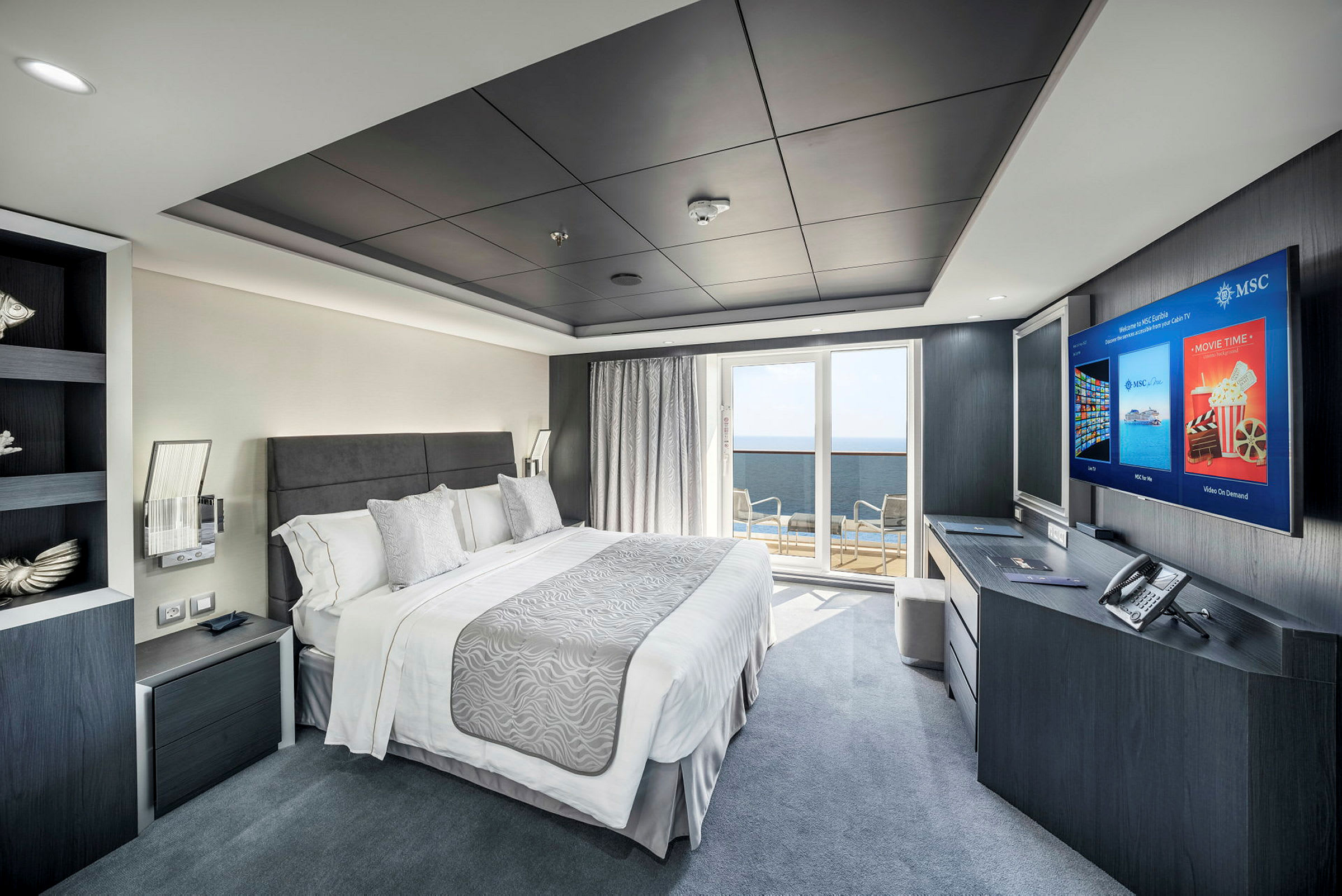 Ett modernt hotellrum med en dubbelsäng, skrivbord med TV, balkong med utsikt och elegant inredning. (AI-genererad text)