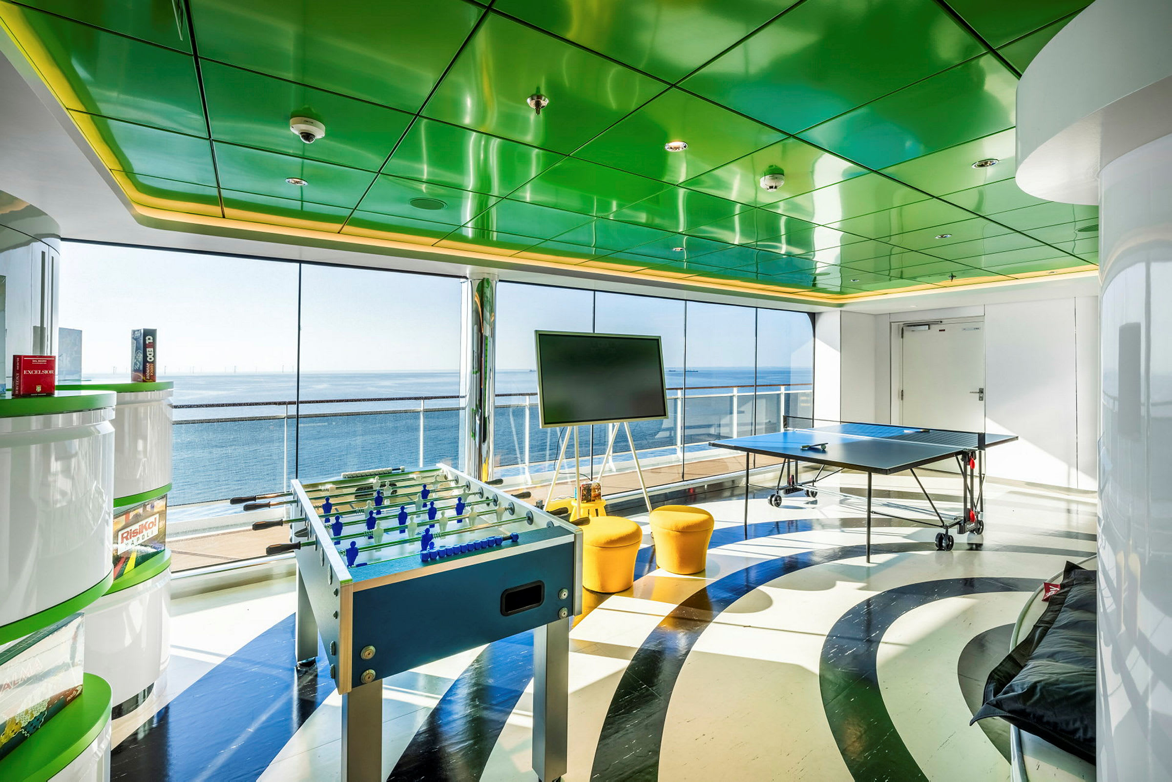 Ett rum med utsikt över havet, innehållande bordtennisbord och fotbollsspel. (AI-genererad text)